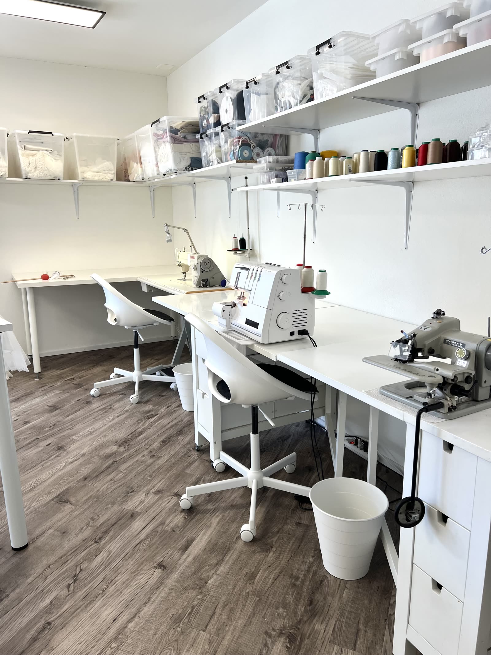 Nähwerkstatt mit Overlock, Industrienähmaschinen und Garnregalen im Atelier