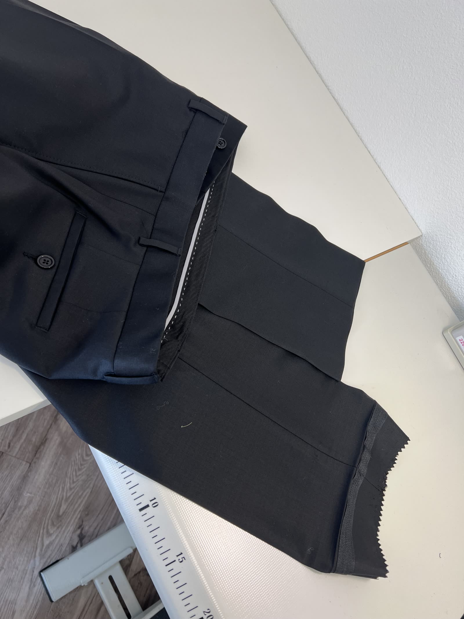 Schwarze Anzugshose bei der Anpassung auf dem Arbeitstisch im Atelier