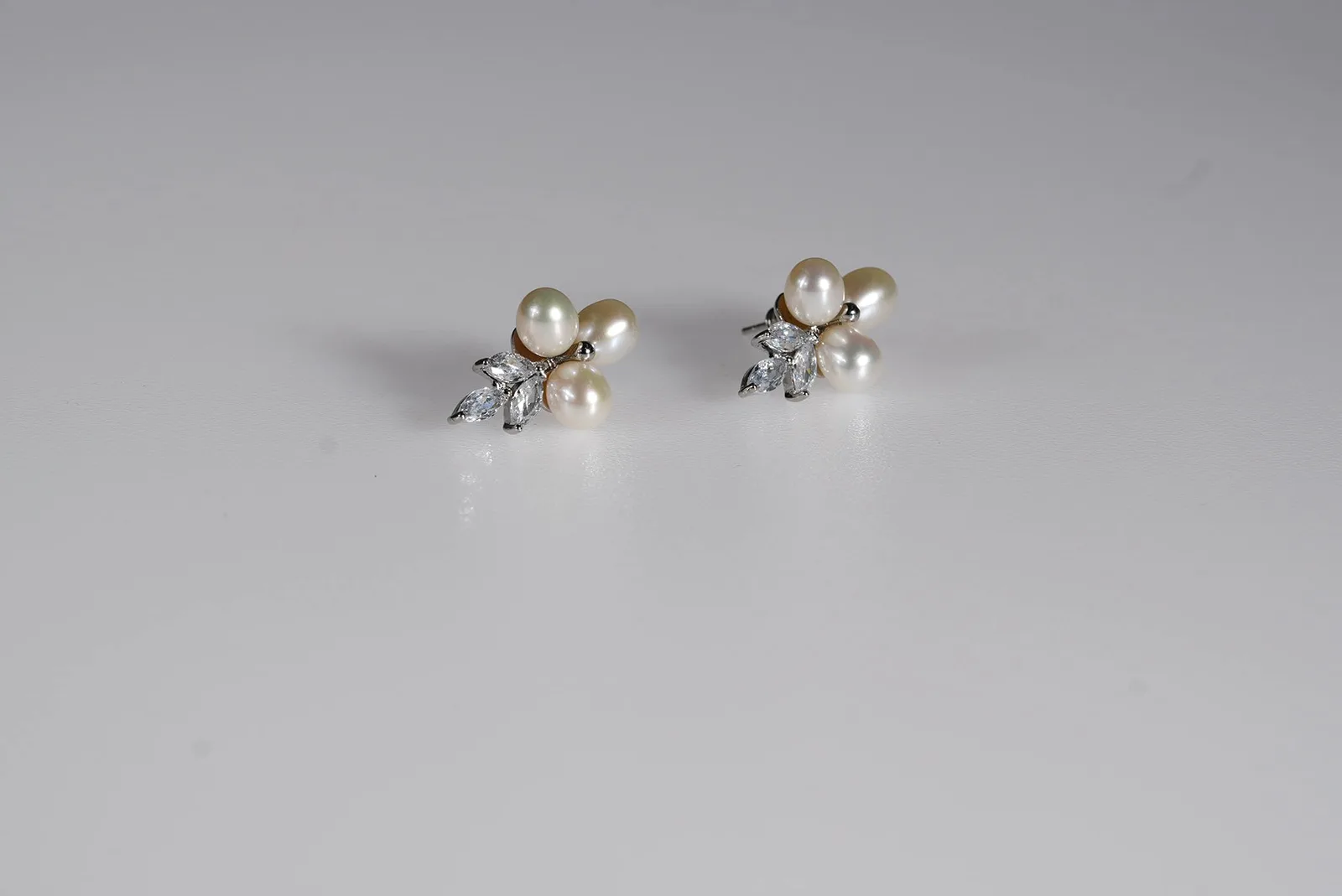 OlesJa Ohrstecker „Pearl Blossom“ mit drei echten Süßwasserperlen in Creme und funkelnden Kristallen in Blattform.