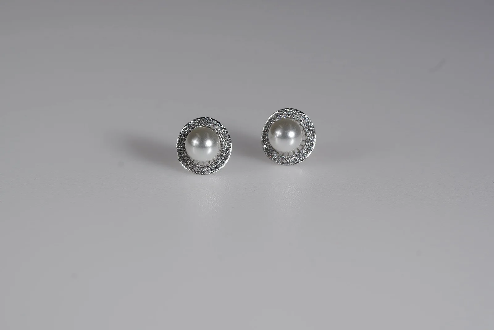 OlesJa Ohrstecker „Pearl Halo“ mit weißer Kunstperle und funkelndem Kristallkranz aus silberfarbenem Qualitätsmetall.