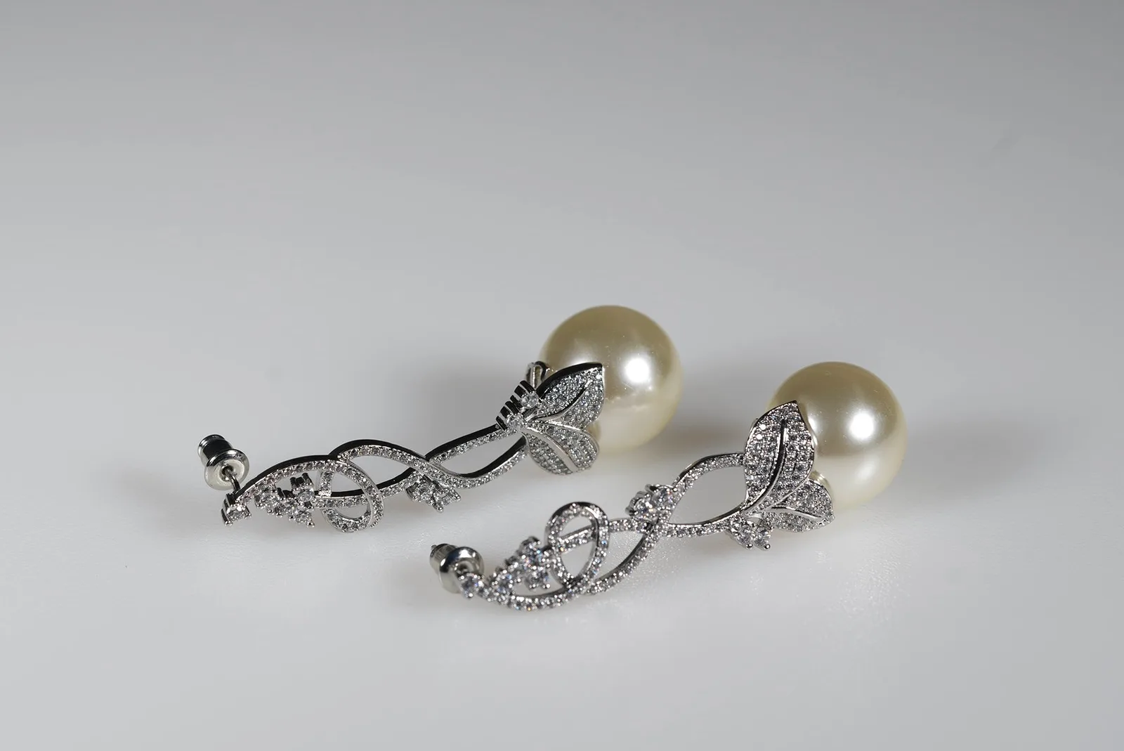 Ohrringe „Pearl Vine“ von OlesJA mit großer Ivory-Kunstperle und funkelnden Strasssteinen in silberfarbenem Ranken-Design.